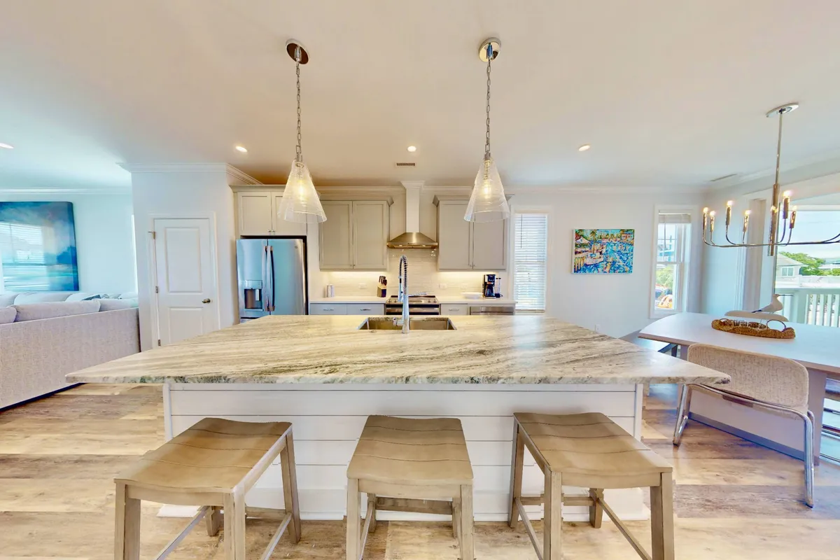 A spacious, open-concept kitchen and dining area featuring a large kitchen island, stainless steel appliances, modern lighting fixtures, and a dining table. The design is contemporary and welcoming, perfect for group cooking and gatherings.