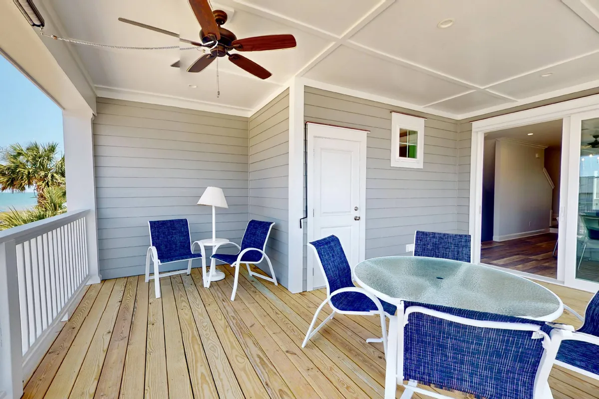An outdoor seating area features a dining table with a stunning ocean view. The space is perfect for groups to gather after a day on the beach, sharing stories, snacks, or meals together with the sound and sight of the ocean in the background.